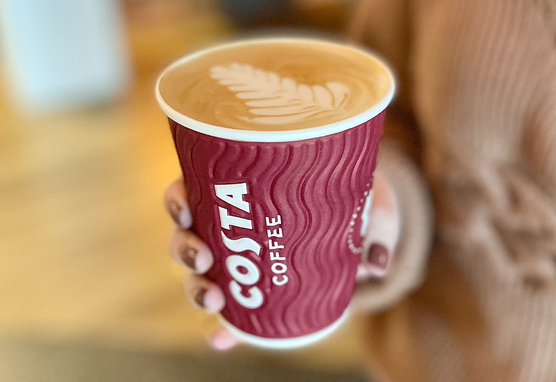 Woman holding a fresh cup of Costa coffee.